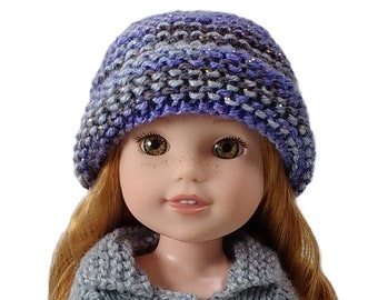 May include: A doll wearing a blue and purple knitted hat with a gray knitted sweater.