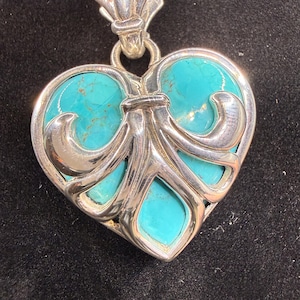 Peut inclure: Un pendentif en forme de cœur doté d'une monture en argent poli avec un motif ornemental en volutes. Le pendentif est incrusté de segments de pierre turquoise vive présentant des veines naturelles brunes. Une bélière en argent relie le collier.