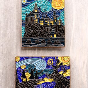 May include: Two enamel pins featuring a starry night design with a castle and figures with wands. The pins have a gold border and are set against a blue, yellow, and black background. The top pin depicts a castle.