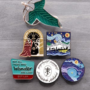 May include: A collection of enamel pins featuring designs from The Lord of the Rings and other fantasy themes. Includes a green leaf, a door, a starry night scene, and pins with text.