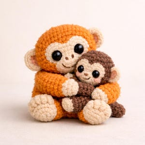 May include: A handmade crochet monkey family, featuring a larger orange monkey hugging a smaller brown monkey. Both have large, black eyes and beige accents. The toys are soft and cuddly, perfect for a child's room or as a unique gift.