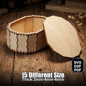 May include: A light-colored wooden box with a removable lid. The box has a unique design with a series of vertical rectangular cutouts. The text "15 Different Size Thick:3mm-4mm-6mm" is visible. The box is on a wooden surface.