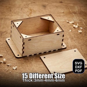 May include: A light-colored wooden box with a separate lid, featuring a square shape and interlocking joints. The box is on a wooden surface. Text on the image reads "15 Different Size Thick: 3mm-4mm-6mm" and "SVG DXF PDF".
