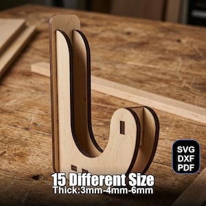 May include: A wooden display stand with a curved design. The stand is made of light-colored wood and features the text "15 Different Size Thick:3mm-4mm-6mm". The stand also has the text "SVG DXF PDF" in a black square.