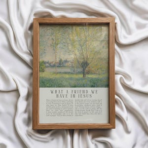 May include: A framed print with a landscape painting of a tree and a body of water. The print has a light brown wooden frame. The text "WHAT A FRIEND WE HAVE IN JESUS" is printed at the bottom.