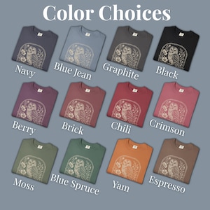 A selection of crew neck t-shirts in various colors, including navy, blue jean, graphite, and black. Each shirt features a beige owl graphic within a floral frame. The text "Color Choices" is at the top, with color names below each shirt.