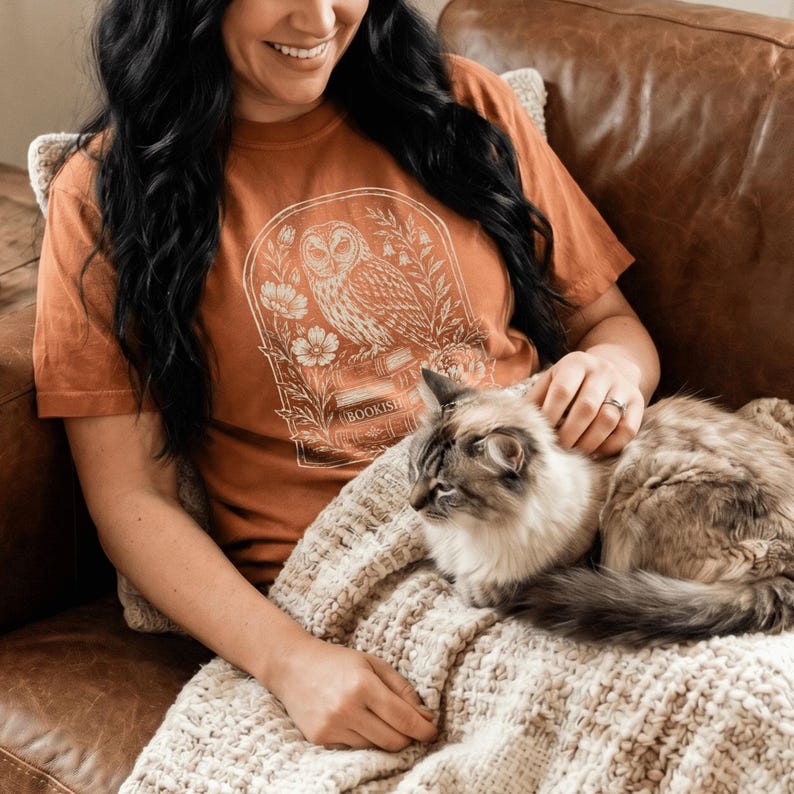 This bookish t-shirt features a vintage linocut botanical owl graphic design printed on a premium Comfort Colors tee, perfect for women book lovers who embrace Dark Academia aesthetics. Whether you're searching for a literary gift for a reader in your life or a vintage Booktok shirt that celebrates bookworm culture, this owl graphic tee captures the magic of living between the pages.