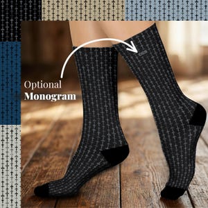 May include: A pair of black crew socks featuring a repeating pattern of small grey crosses. The socks have solid black heels and toes. The text "Optional Monogram" is visible with an arrow pointing to the "CGS" monogram on the upper sock.