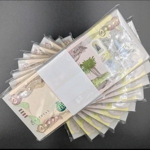 Peut inclure: Plusieurs liasses de billets de banque de 50 dirhams des Émirats arabes unis (EAU) sont présentées en éventail. Les billets sont dans un emballage plastique transparent et maintenus par une bande de papier blanche. Ils présentent du texte arabe et des motifs.