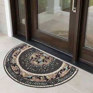 Puede incluir: Una alfombra de puerta semicircular con un diseño de mosaico. La alfombra presenta un patrón espiral central en tonos marrones, negros y beige, con detalles florales y de pájaros en negro y azul claro. La alfombra está colocada frente a una puerta marrón oscuro.