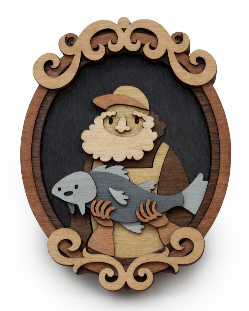 Puede incluir: Obra de arte de madera en capas que representa a un pescador sosteniendo un pez. La obra est&aacute; enmarcada en una forma ovalada decorativa con un fondo oscuro. El pescador lleva un sombrero y un delantal, y el pez es gris.