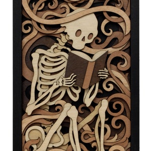 May include: A wooden wall art piece featuring a skeleton sitting and reading a book. The skeleton is surrounded by intricate, layered wood carvings of swirling patterns. The piece is framed in black wood.