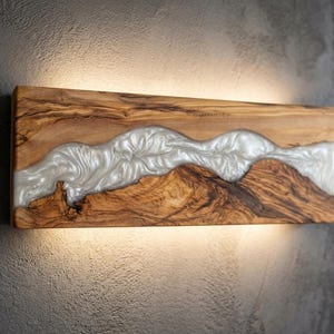 Op de afbeelding: Een witte keramische mok met een zwart handvat en de tekst "But First, Coffee" in een zwarte, vette letter. De mok staat op een houten oppervlak. De mok is ongeveer 10 cm hoog.