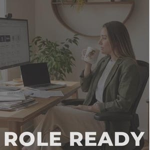 Pode incluir: Uma mulher sentada numa secretária, segurando uma caneca, com um laptop e um monitor de computador. O texto "ROLE READY" é exibido na parte inferior da imagem, juntamente com um endereço de site. A mulher está vestindo um blazer.