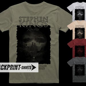 Op de afbeelding: Een t-shirt met korte mouwen en ronde hals in olijfgroen, wit, beige, bordeauxrood en antracietgrijs. De voorkant heeft een grafische print met de tekst "STEPHEN KING'S Rose Red" boven een donkere, sfeervolle afbeelding van een huis.