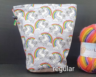 Peut inclure: Un sac à cordon gris avec un motif de licorne et d'arc-en-ciel. Le sac est rempli de laine colorée.