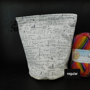 May include: A white drawstring bag with a black and white print of mathematical formulas and equations. The bag is next to a ball of rainbow colored yarn.