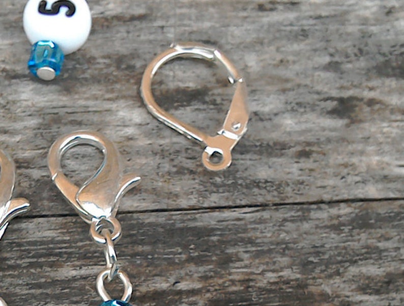 May include: Two silver-toned earring hooks. One hook is a simple loop, the other is a lobster claw clasp.