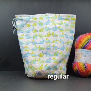May include: White drawstring bag with a blue and yellow bunny pattern. The bag is labeled "regular".