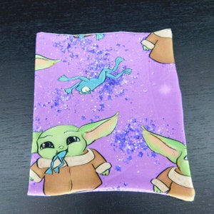 May include: Purple fabric with a repeating pattern of a green character with large ears wearing a brown coat and a green frog. The character is holding the frog in its mouth. The background is a purple glitter pattern.