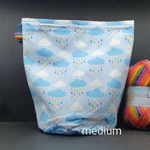 Peut inclure: Un sac à cordon bleu avec un motif de nuages blancs et de gouttes de pluie. Le sac est étiqueté "moyen".
