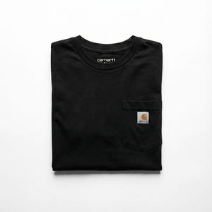 May include: Black Carhartt t-shirt with a chest pocket and the Carhartt logo. The shirt is folded neatly on a white background. The Carhartt logo is a square patch with the brand name.