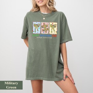 Könnte beinhalten: Militärgrünes T-Shirt mit einer farbenfrohen Grafik zur Förderung des Autismus-Bewusstseins. Die Grafik zeigt drei rechteckige Designs mit Schleifen und einer Nähmaschine sowie den Text "Know, Understand, Love - autism awareness."