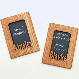 May include: Two wooden picture frames with black mats and white text. The frame on the left says "Small Magnets Ainsley". The frame on the right says "Outside: 2 1/2 x 3 1/2 Inside: 1 1/2 x 2 1/2 Blayke".