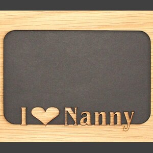 Può includere: Cornice per foto in legno con sfondo nero e il testo "I love Nanny" inciso nel legno.