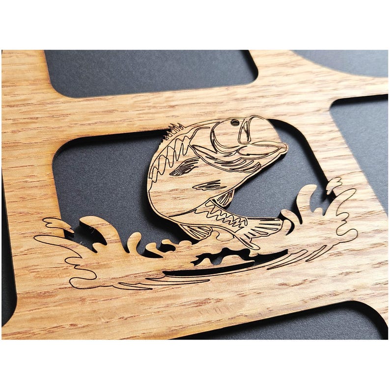 May include: A light brown wooden cutout featuring a laser-engraved design of a fish jumping out of water. The fish is depicted in a stylized manner with visible scales and fins, surrounded by carved water splashes, set within a larger wooden frame.