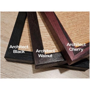 May include: Three wooden picture frames with mitered corners, labeled Architect Black, Architect Walnut, and Architect Cherry. Each frame features a distinct wood grain texture and color, ranging from deep black to dark brown and reddish-brown tones.