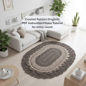 May include: A handmade oval crochet rug in grey and beige tones. The rug, with a detailed openwork pattern and scalloped edge, sits on a light wood floor. The text "Crochet Pattern (English)" is visible.