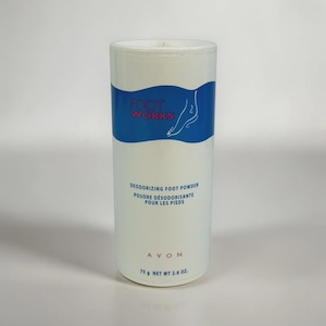 Puede incluir: Un envase cilíndrico blanco de polvos desodorantes para pies Avon Foot Works. La etiqueta presenta un diseño de onda azul, el contorno blanco de un pie y el texto Foot Works, Deodorizing Foot Powder, Avon y 75 g.