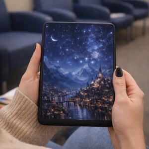 May include: A black tablet displaying a digital art scene of a night sky with a crescent moon, mountains, and a city. The tablet is held in a person's hands, with a neutral background.