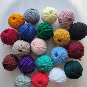 May include: A collection of 20 balls of yarn in various colors, including red, green, blue, yellow, purple, brown, white, black, and gray. The yarn is arranged in a circle on a white surface.