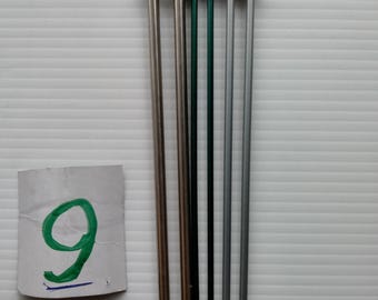 May include: Five knitting needles with silver tips and different colored shafts: silver, silver, green, silver, and silver.