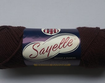 May include: A brown ball of Sayelle yarn, a 100% DuPont Orlon acrylic worsted weight yarn. The label reads "Sayelle" and "Weight 4 ounces". The yarn is machine washable.