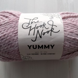 May include: A skein of light pink yarn labeled "The Hook Nook Yummy yarn fil hilo 3.5 oz [100 grams] 106 yards [170 meters]"