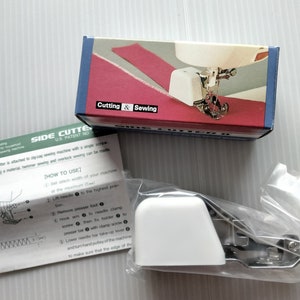 May include: A sewing machine side cutter attachment with a white plastic cover and metal components. The box reads "Cutting & Sewing" and shows a diagram of the attachment in use. Instructions are included.