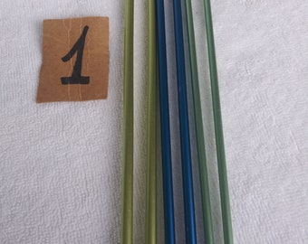 May include: A set of six knitting needles in various shades of green and blue. The needles have silver metal tips.