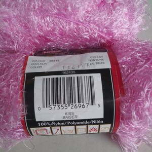 May include: A pink ball of yarn with a label that reads "Kiss Baiser" and "100% Nylon/Polyamide/Nil&oacute;n". The label also includes a barcode and the numbers "35415", "1361", and "162435".