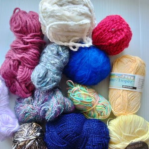 May include: A collection of yarn balls in various colors, including pink, blue, yellow, white, and multi-colored. The yarn is arranged in a circle on a white surface. Some of the yarn balls have labels with the brand name "Filatura di Crosa" and the text "Saint-Tropez" and "almedahts".
