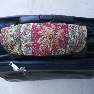 May include: Black leather briefcase with a patterned fabric handle. The fabric is red, green, and gold with a floral design.