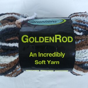 May include: A skein of GoldenRod yarn in a brown, white, and blue color scheme. The yarn is soft and fluffy, and the label reads "Sensations™ GoldenRod An Incredibly Soft Yarn".