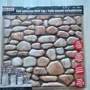 May include: A package of self-adhesive wall tile with a stone pattern. The tile is 12 inches by 30.4 centimeters and is great for kitchens and bathrooms. The package shows a close-up of the tile and has instructions on how to use it.