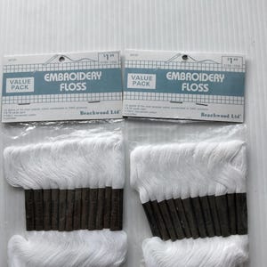 May include: Two packages of white embroidery floss. Each package has a blue and white label that reads "Embroidery Floss" and "Value Pack". The floss is packaged with brown cardboard. The text "Beachwood Ltd" is printed on the label.