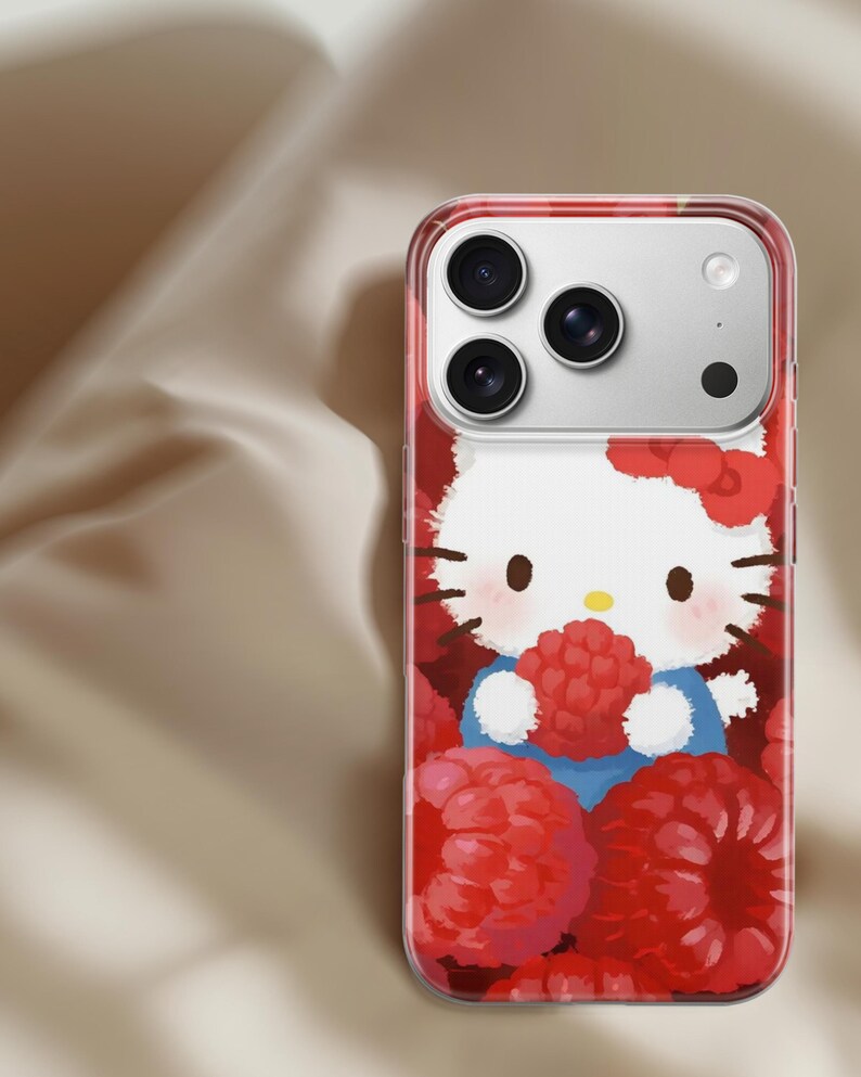 May include: Clear phone case featuring a cartoon image of Hello Kitty holding a raspberry. The case has a red border and a background filled with red raspberries. The phone's camera lenses are visible at the top.