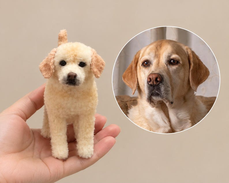 May include: A small, needle-felted cream-coloured dog figurine with a textured wool finish, dark eyes, and a brown nose, displayed alongside a circular inset photograph of a real yellow Labrador retriever with similar facial features.