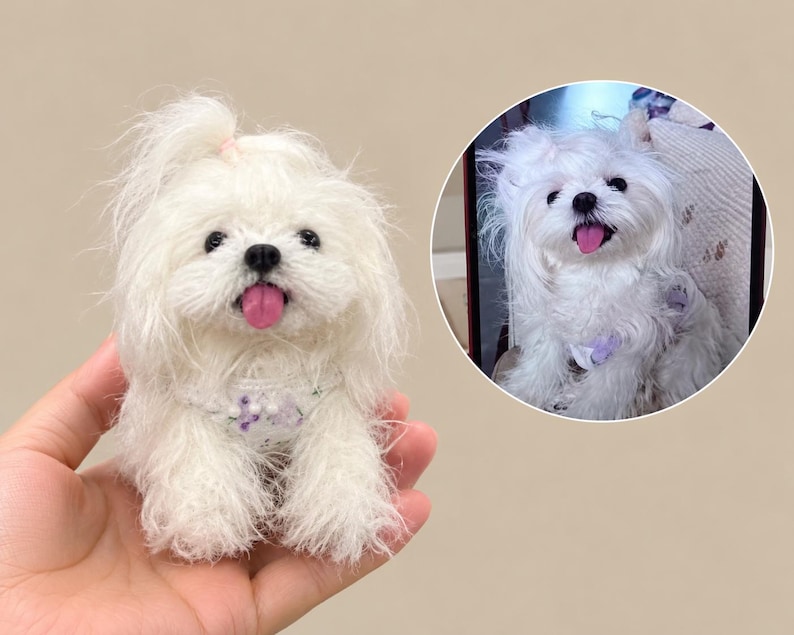 May include: A small, white, fluffy, needle-felted dog figurine with a pink tongue, black nose, and a small hair tie on its head. It wears a decorative collar with purple accents. A circular inset shows a photograph of a real white dog.