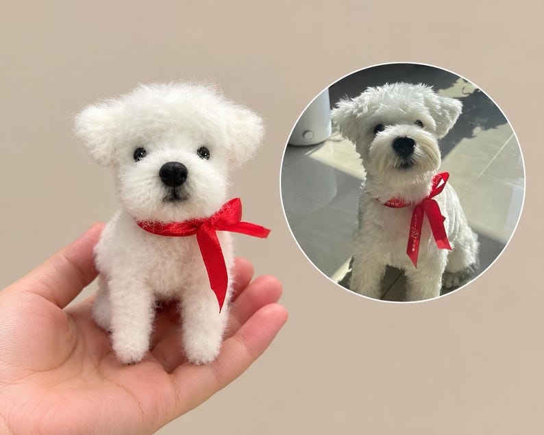 May include: A small, white, needle-felted dog figurine with a black nose and eyes, wearing a bright red satin ribbon tied in a bow around its neck. Beside it is a circular inset photo of a real white dog wearing an identical red ribbon.